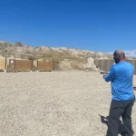 man in blue shirt target practice with gun