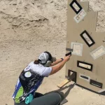 Woman learning to shoot gun behind obstacle