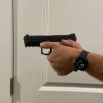 Hands holding pistol in front of door