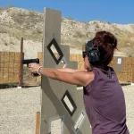 Woman purple shirt learning to shoot gun